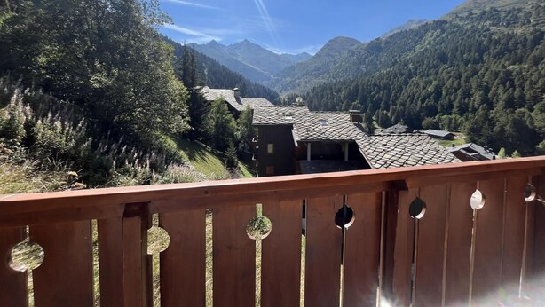 A balcony with a view of a valley, mountains, and a house with a tiled roof. - 180m from ski slopes, floor -1, view mountain, balcony, tv, 37m², Méribel-Mottaret (Méribel - Les Allues)