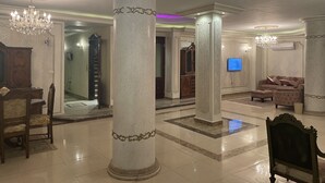 A spacious lobby with large columns, a chandelier, a television, and a sofa. - Fancy 3 bedrooms  240 m apartment in sheik zayed compound (6th of october)