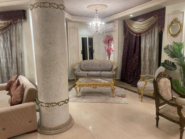 A luxurious living room with a grand chandelier, ornate furniture, and a large column. - Fancy 3 bedrooms 240 m apartment in sheik zayed compound (6th of october)