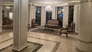 A spacious lobby with ornate columns, a grand chandelier, and a large window. - Fancy 3 bedrooms  240 m apartment in sheik zayed compound (6th of october)