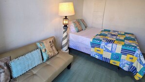 A bedroom with a bed, a sofa, a lamp, and a painting on the wall. - Studio Lighthouse, Walking - 10 min to the beach (Noord)