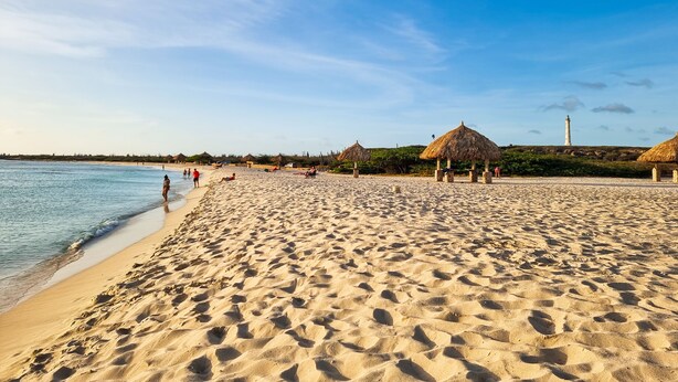 A beach with thatched-roof huts, a lighthouse, and people relaxing. - Studio Lighthouse, Walking - 10 min to the beach (Noord)