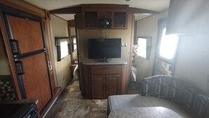 Interior compacto de una autocaravana con kitchenette, televisor y zona de estar.