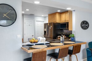 Una cocina moderna con armarios de madera, electrodomésticos de acero inoxidable y un reloj negro en la pared.