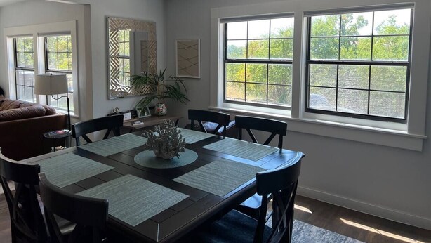 A dining area with a table set for four, surrounded by chairs, with a decorative centerpiece.