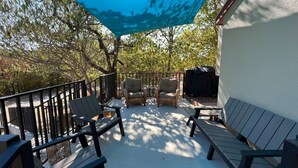 An outdoor patio with black chairs and a table, a blue canopy, and a barbecue grill.