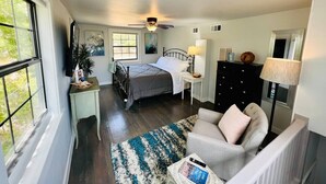 A bedroom with a bed, bedside table, lamp, and a dresser.