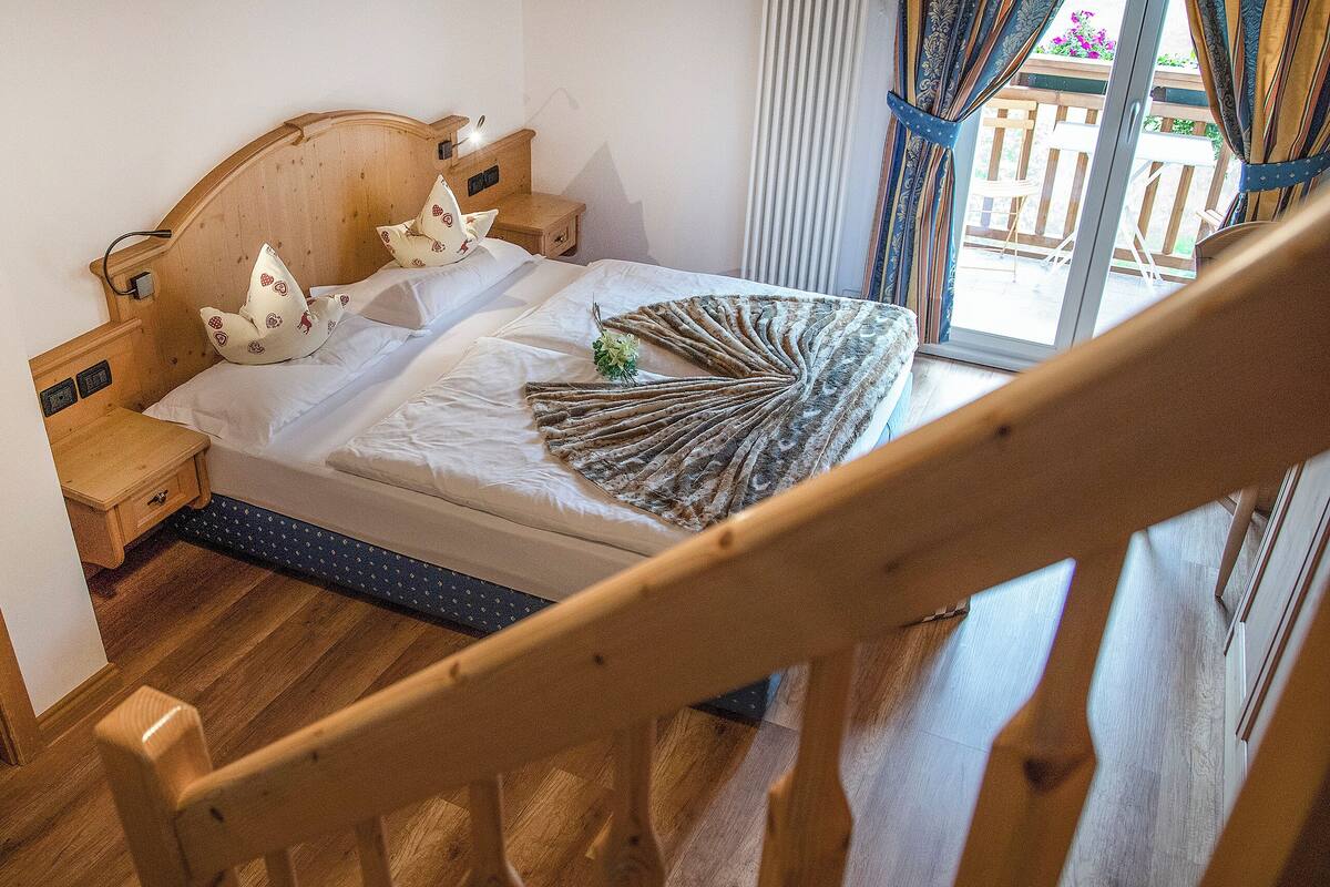 Un lit en bois avec une tête de lit, une table de chevet et un éventail décoratif posé sur le lit.