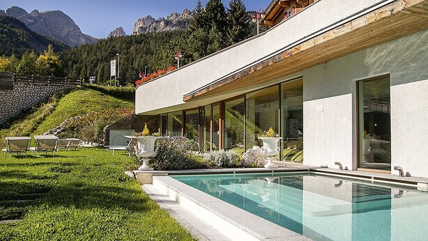 Un bâtiment moderne doté d’une piscine, d’un espace extérieur aménagé et offrant une vue sur les montagnes.
