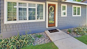 A modern house with large windows, a wooden front door, and a 'hello' mat.