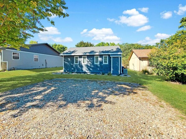 A two-story house with a gravel driveway and a lawn.