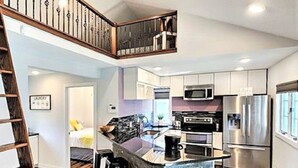 A modern kitchen with a central island, stainless steel appliances, and a wooden floor.