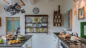 A kitchen with a stove, shelves with plates, and a clock on the wall. - Casa Antonio - Private villa, 4 bedrooms, pool, A/C, wifi, pets, Marche (Mogliano)
