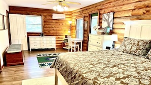 Un dormitorio de cabaña de madera con cama, cómoda, escritorio y silla.