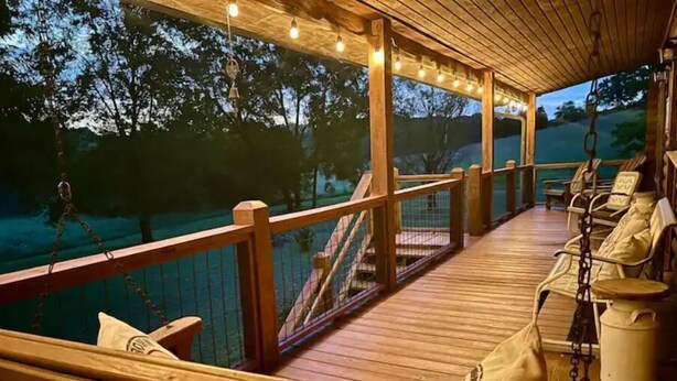 Terraza de madera con asientos y barandilla con vista al agua.