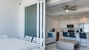 Een moderne keuken met witte kastjes, een magnetron en een koelkast. Er is een eethoek met een witte tafel en stoelen.