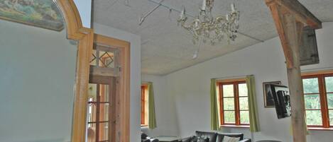 A room with a wooden door, a black leather sofa, a small wooden table, and a chandelier.