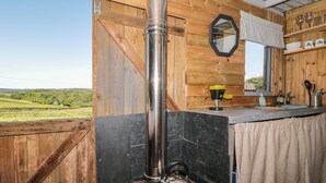 A rustic bathroom with a wood interior, a large mirror, and a view of the countryside. - The Snug (Dulverton)