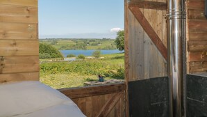 A wooden cabin with a view of a lake and surrounding greenery. - The Snug (Dulverton)