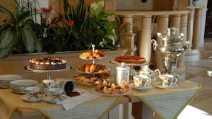 A buffet table with various food items, tea service, and a decorative silver urn. - Hotel Alle Alpi (Moena)