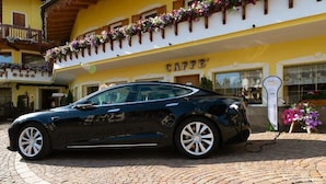 A black car parked in front of a yellow building with a sign that reads "CAFFE'". - Hotel Alle Alpi (Moena)