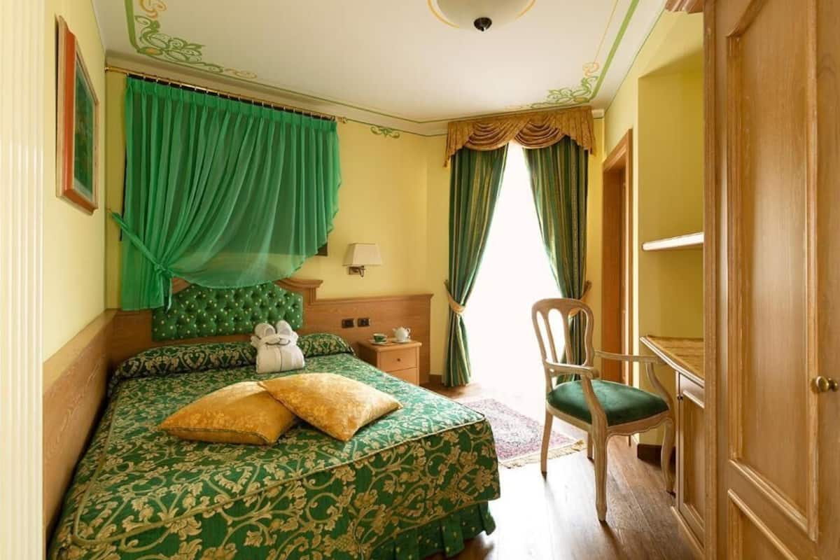 A bedroom with a bed, a chair, a nightstand, and a wardrobe.