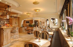 Un restaurant doté d’un bar, de meubles en bois et d’un sol carrelé.