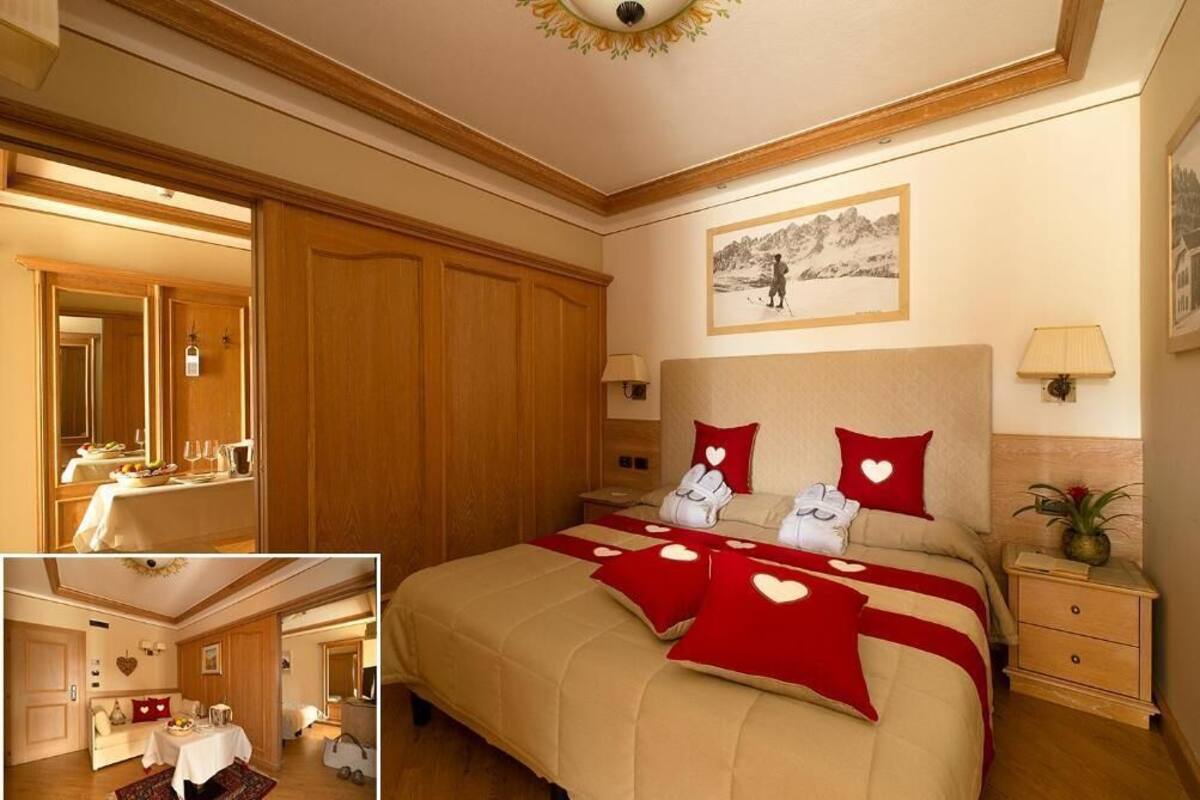 A hotel room with a large bed, a dining area, and a bathroom.