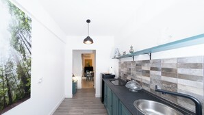 Et snævert køkken med mørke bordplader, en stålvask og et flisebeklædt bagpanel.