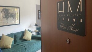 Et værelse med en grøn sofa, et indrammet kunstværk og en dør med skiltet “HOME RETREAT”.