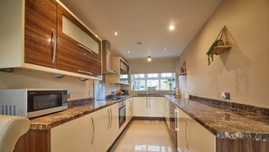 A modern kitchen with wooden cabinets, a granite countertop, and stainless steel appliances. - Host Stay Stonehaven (Hartlepool)