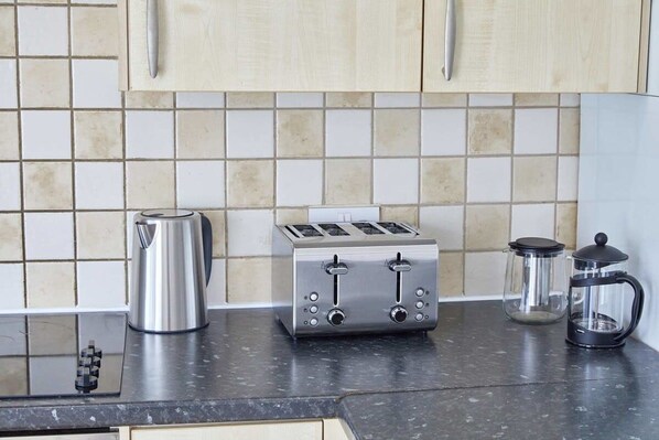 A kitchen with a toaster, a coffee maker, and a glass container on the counter. - Host Stay Seafarers (Seahouses)