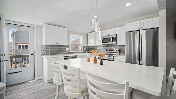 A modern kitchen with white cabinetry, stainless steel appliances, and a central island with seating. - Full House- 2 Blocks from Beach! (Brigantine)