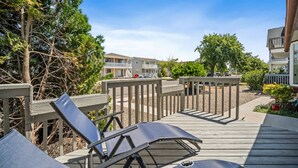 A wooden deck with lounge chairs, a railing, and a view of a residential area with buildings and trees. - Full House- 2 Blocks from Beach! (Brigantine)
