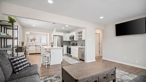 A modern living room with a grey sofa, a wooden coffee table, and a kitchen in the background. - Full House- 2 Blocks from Beach! (Brigantine)