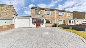 A two-story residential building with a garage, a paved driveway, and a well-maintained garden. - Host Stay Shorty s (Morpeth)