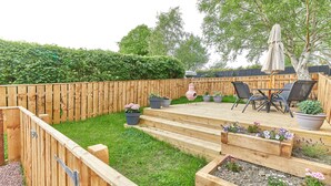 A wooden deck with a seating area, raised flower beds, and a wooden fence.