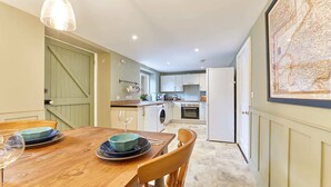 A compact kitchen with a dining area, a washing machine, and a refrigerator.