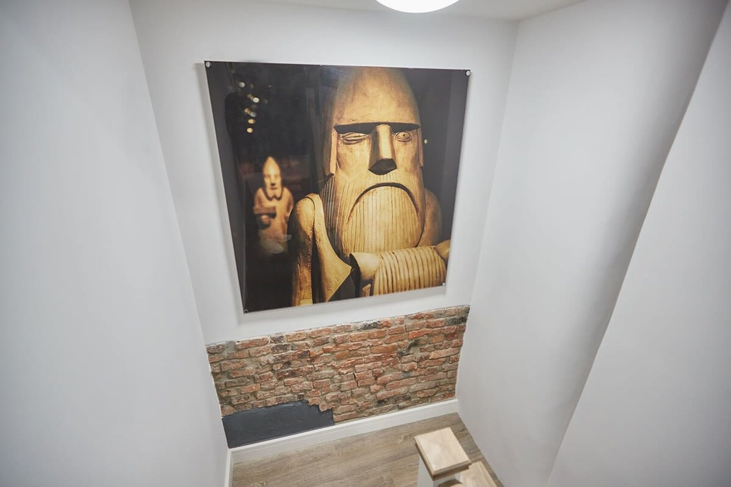 Une pièce avec un mur en briques et un grand tableau représentant une figure.