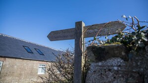 A wooden signpost with directions to 'Public Footpath,' 'Spindlestone,' and 'Lucker 172.' - Host Stay No 2 Lavender Cottage (Belford)