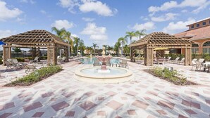A pool area with two pergolas, lounge chairs, and a central fountain. - Bellavida Resorts 9 Themed bd Private Pool Disney (Kissimmee)