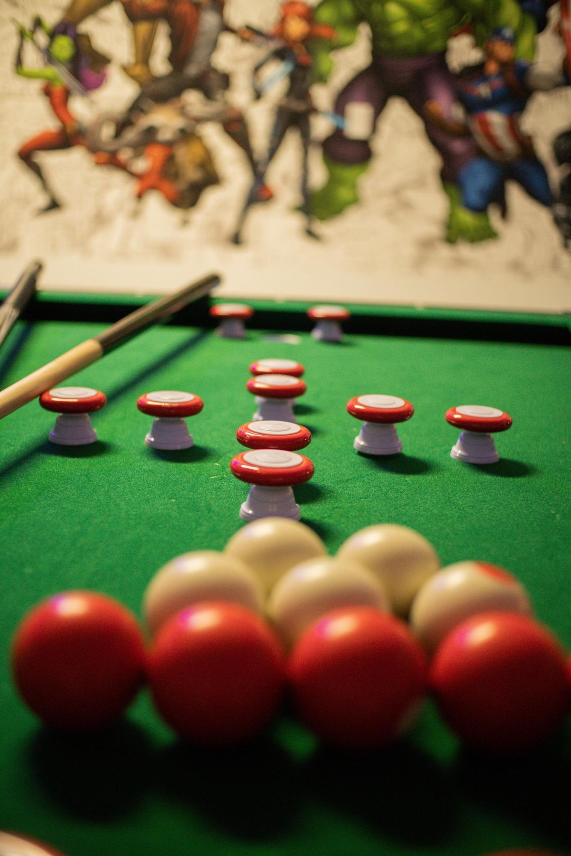 Gros plan d’une table de billard avec des billes rouges et blanches et un queue de billard.
