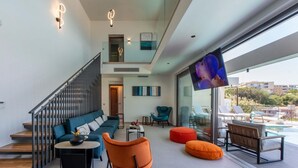 A modern living room with a staircase, seating area, and a large window overlooking a pool. - Lusol Seafront Villa Ii-free Heated Pool 100m Sea (Chania)
