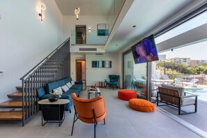 Uma sala de estar moderna com escada, área de estar e uma grande janela com vista para uma piscina.