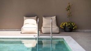 A pool area with two beige chairs, a potted plant with yellow flowers, and a clear pool. - Lusol Seafront Villa Ii-free Heated Pool 100m Sea (Chania)