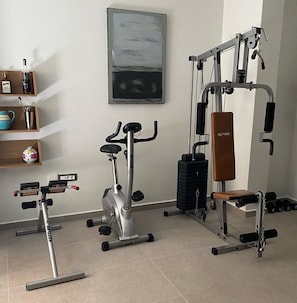 Uma academia em casa com uma máquina elíptica, um banco de musculação e uma estrutura para agachamento.
