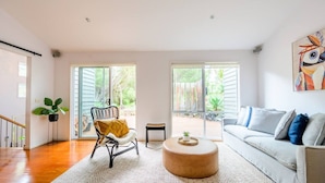 A modern living room with a sofa, a round coffee table, and a chair. There are large windows providing a view of the outdoors. - Retreat, short drive to Beach (Rye)