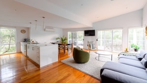 A spacious living area with a kitchen, dining table, and a large window. - Retreat, short drive to Beach (Rye)