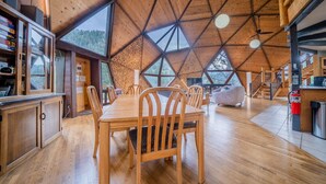 A spacious dining area with a wooden table and chairs, large windows, and a high ceiling with a geometric design. - The Legendary Snow Globe of Estes Park (Estes Park)