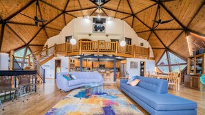 A spacious loft with a high ceiling, wooden beams, a balcony, and a colorful abstract rug. - The Legendary Snow Globe of Estes Park (Estes Park)